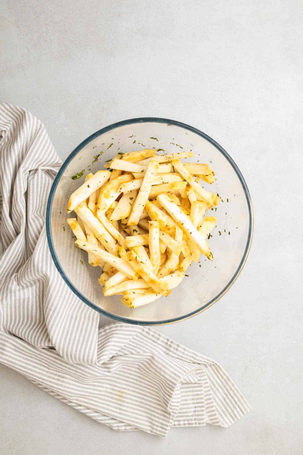 Patatine fritte condite in olio e rosmarino in una ciotola di vetro, vista dall'alto