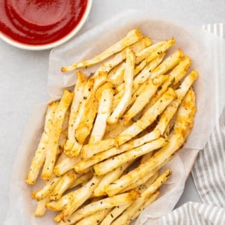 Primo piano di patate fritte di sedano in un cestino accanto a un ramekin di ketchup