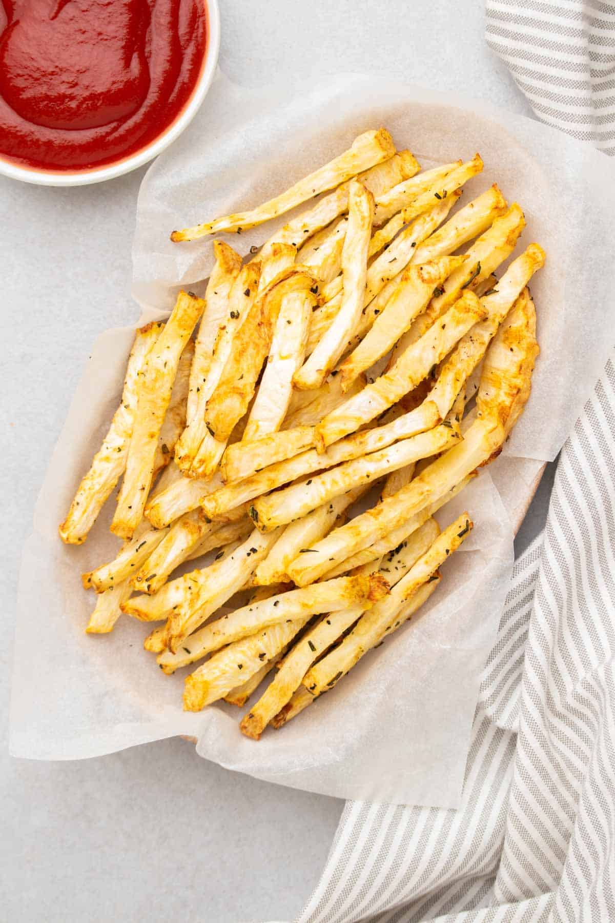 Vista dall'alto delle patatine fritte in un cestino accanto a un ramekin di ketchup