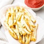 Primo piano di patate fritte di sedano in un cestino accanto a un ramekin di ketchup