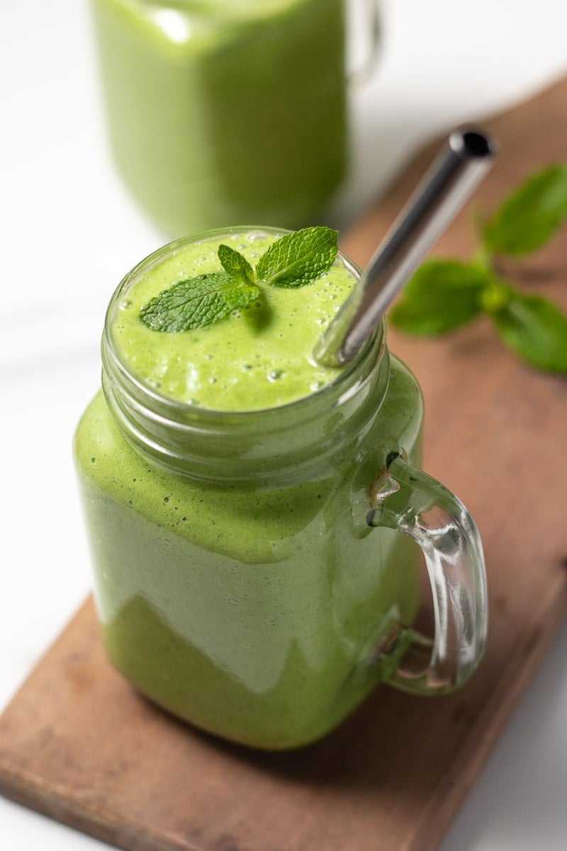 Frullato di keto verde in un bicchiere con una cannuccia e guarnito con menta